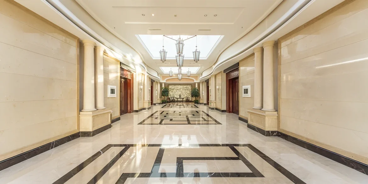 An elegant hotel corridor featuring marble flooring, neoclassical columns, and ornate chandeliers, showcasing the craftsmanship of a premier Interior Fit Out Company in Dubai.